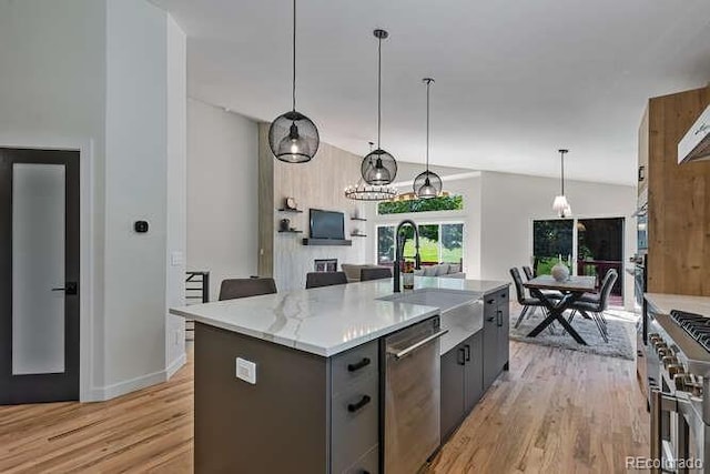 9561 Silver Hill Cir, Lone Tree, CO 80124 - kitchen featuring appliances with stainless steel finishes, light wood-style floors, a center island with sink, pendant lighting, and light stone countertops