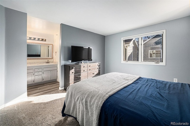 carpeted bedroom featuring sink and ensuite bath