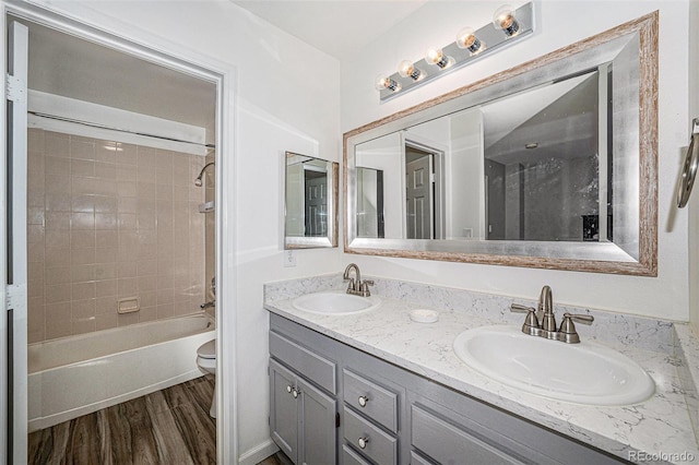 full bathroom with toilet, wood-type flooring, vanity, and tiled shower / bath