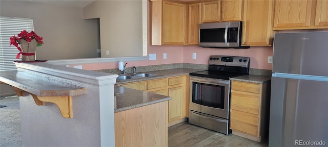 kitchen featuring sink, stainless steel appliances, kitchen peninsula, light hardwood / wood-style floors, and light brown cabinetry