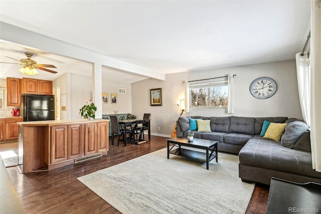 living room with beamed ceiling, dark wood-type flooring, and ceiling fan