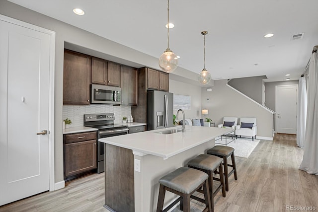 23615 E 5th Pl, Aurora, CO 80018 - kitchen featuring appliances with stainless steel finishes, a sink, light wood-style flooring, backsplash, and light countertops