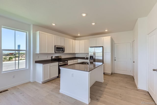752 N Bently St, Watkins, CO 80137 - kitchen with stainless steel appliances, dark countertops, light wood-type flooring, recessed lighting, and a kitchen island with sink