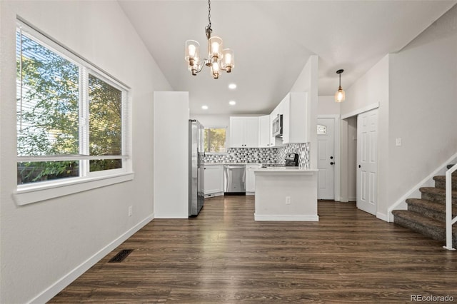 kitchen with white cabinets, stainless steel appliances, hanging light fixtures, and dark hardwood / wood-style floors