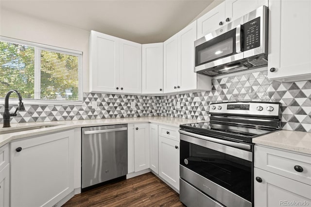 kitchen with tasteful backsplash, dark hardwood / wood-style flooring, white cabinetry, light stone countertops, and stainless steel appliances