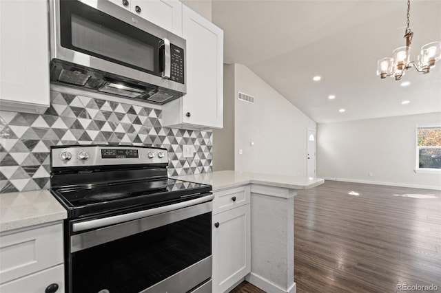 kitchen with white cabinets, tasteful backsplash, appliances with stainless steel finishes, vaulted ceiling, and dark wood-type flooring