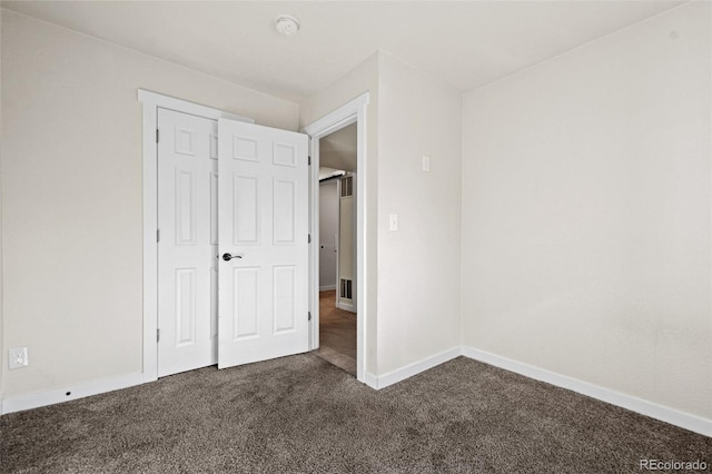 unfurnished bedroom featuring a closet and dark colored carpet