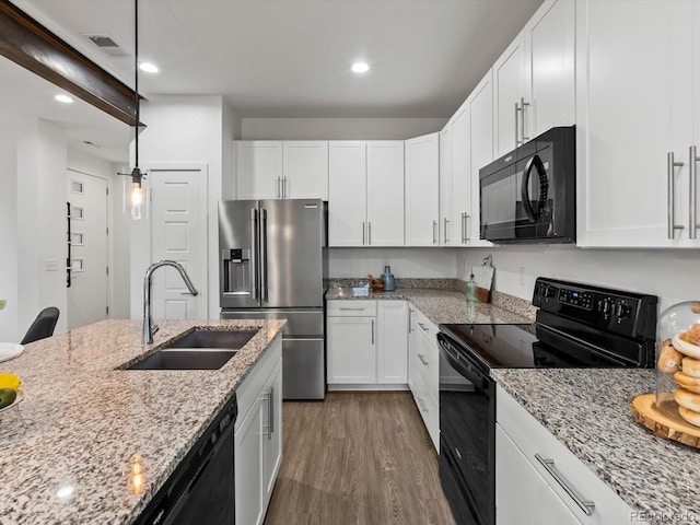 11719 W 45th Pl, Wheat Ridge, CO 80033 - kitchen featuring black appliances, a sink, wood finished floors, white cabinets, and light stone countertops