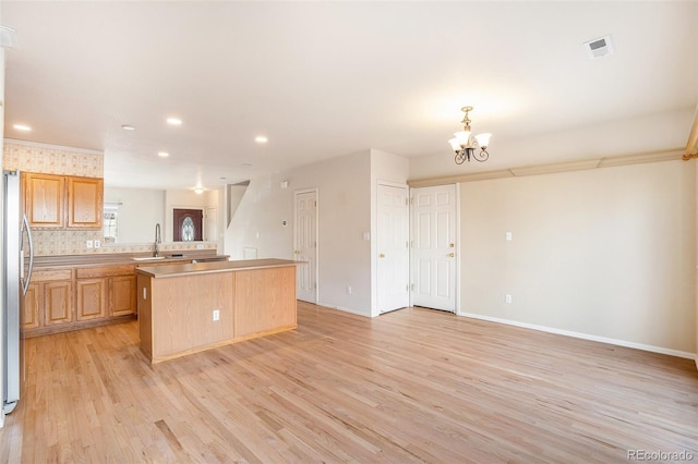 kitchen with visible vents, light wood finished floors, a sink, light countertops, and a center island