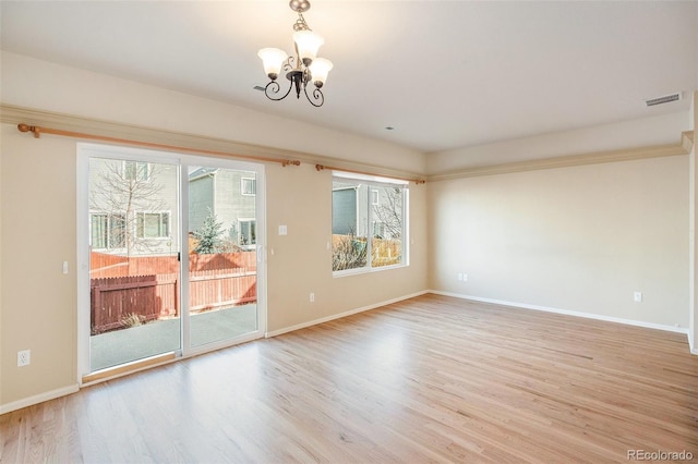 spare room featuring an inviting chandelier, baseboards, and light wood finished floors