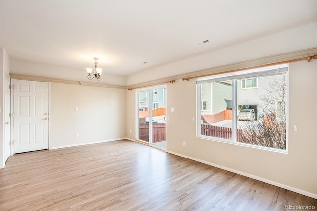 spare room with light wood-type flooring, visible vents, baseboards, and an inviting chandelier