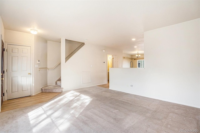 unfurnished living room featuring recessed lighting, carpet flooring, and stairs