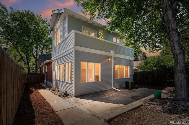 1260 S Emerson St, Denver, CO 80210 - back of property at dusk with a patio, a fenced backyard, and central AC