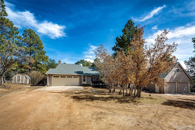 view of front of house with a shed, driveway, a chimney, and an outdoor structure