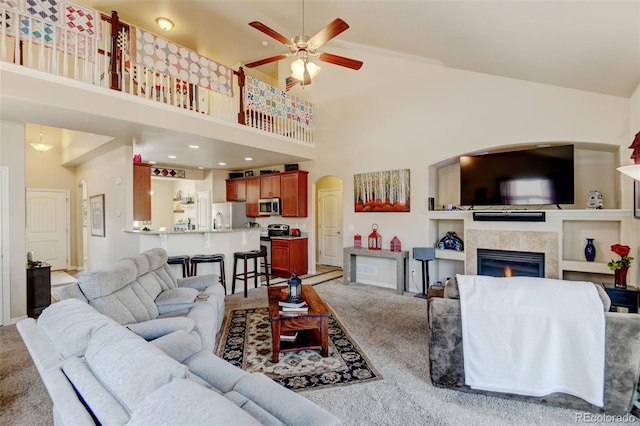 9046 Sandpiper Dr, Frederick, CO 80504 - living room featuring light carpet, ceiling fan, high vaulted ceiling, a tiled fireplace, and arched walkways