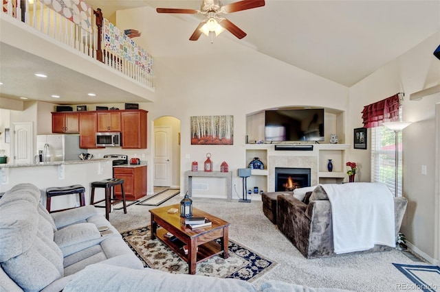 9046 Sandpiper Dr, Frederick, CO 80504 - living room with high vaulted ceiling, ceiling fan, a fireplace, arched walkways, and baseboards