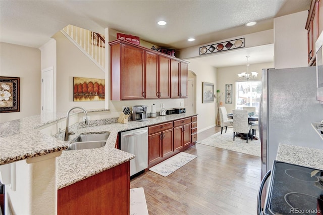 9046 Sandpiper Dr, Frederick, CO 80504 - kitchen with appliances with stainless steel finishes, a sink, a peninsula, light wood-style flooring, and a chandelier