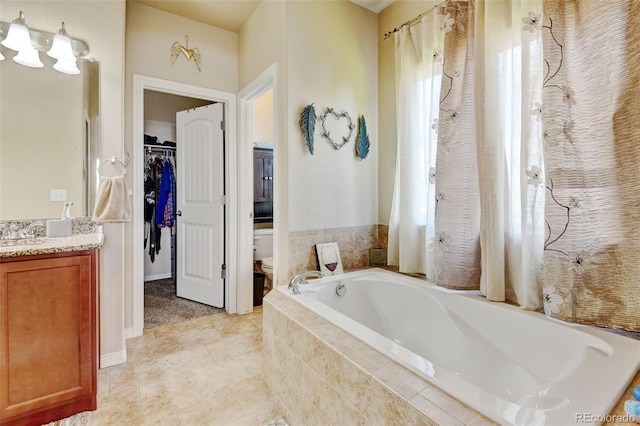 9046 Sandpiper Dr, Frederick, CO 80504 - bathroom featuring vanity, a garden tub, toilet, tile patterned flooring, and a walk in closet