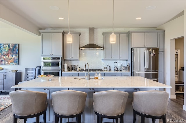 kitchen with a kitchen bar, decorative backsplash, wall chimney exhaust hood, stainless steel appliances, and pendant lighting