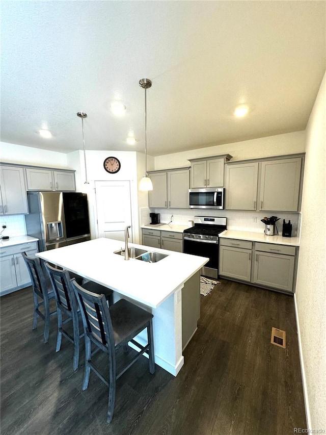 kitchen with decorative light fixtures, stainless steel appliances, visible vents, light countertops, and a sink