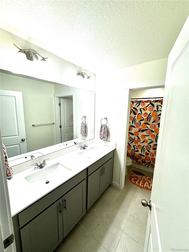 full bath with a sink, a textured ceiling, toilet, and double vanity