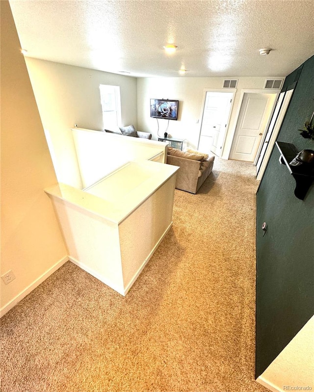 interior space with a textured ceiling, carpet, visible vents, and baseboards