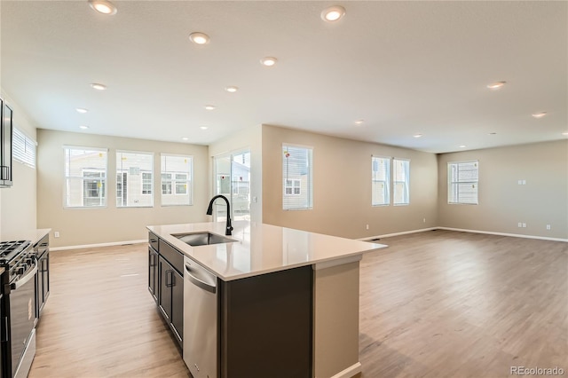 4114 Estrella St, Brighton, CO 80601 - kitchen featuring appliances with stainless steel finishes, light wood-type flooring, light countertops, an island with sink, and recessed lighting
