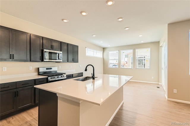 4114 Estrella St, Brighton, CO 80601 - kitchen featuring appliances with stainless steel finishes, light wood-style floors, a center island with sink, light countertops, and recessed lighting