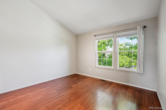 9679 W Chatfield Ave Unit C, Littleton, CO 80128 - spare room with baseboards, wood finished floors, and vaulted ceiling