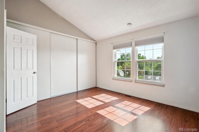 9679 W Chatfield Ave Unit C, Littleton, CO 80128 - unfurnished bedroom with wood finished floors, lofted ceiling, a closet, and a textured ceiling