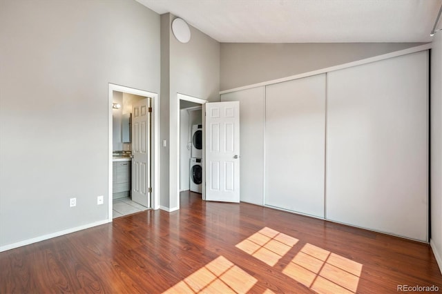 9679 W Chatfield Ave Unit C, Littleton, CO 80128 - unfurnished bedroom with stacked washer / drying machine, wood finished floors, a closet, high vaulted ceiling, and ensuite bathroom