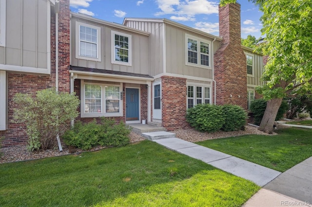 9679 W Chatfield Ave Unit C, Littleton, CO 80128 - view of front facade featuring a front yard, board and batten siding, and brick siding