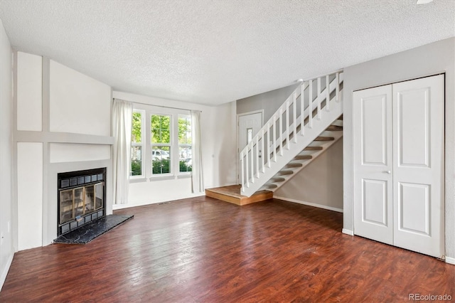 9679 W Chatfield Ave Unit C, Littleton, CO 80128 - unfurnished living room featuring stairs, wood finished floors, a textured ceiling, a glass covered fireplace, and baseboards