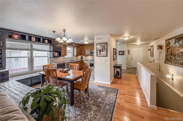 13642 Wrangler Way, Mead, CO 80542 - dining area featuring a chandelier, light wood-type flooring, and a textured ceiling