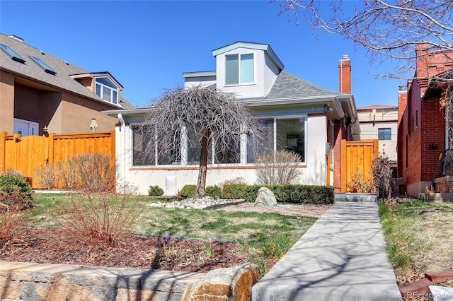 view of front facade featuring a shingled roof, fence, and stucco siding