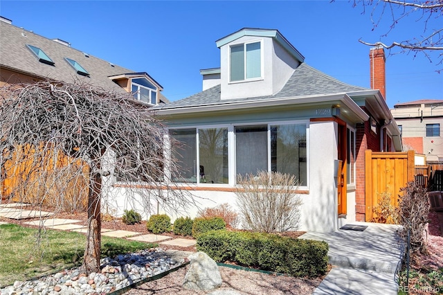 view of front of home featuring a shingled roof, fence, and stucco siding