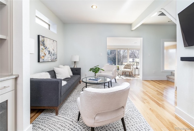 living room with beam ceiling, light wood-style flooring, and baseboards