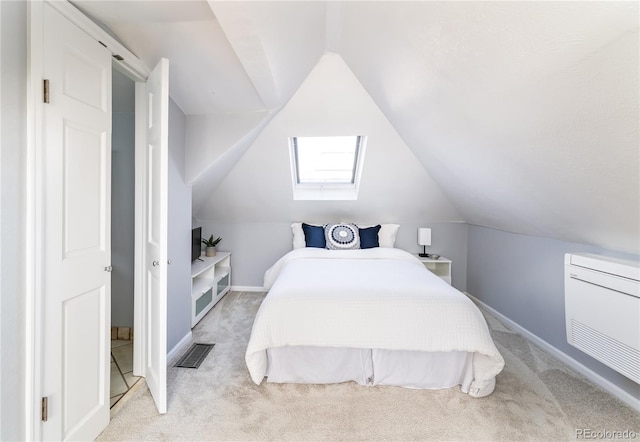 bedroom featuring baseboards, vaulted ceiling with skylight, visible vents, and light colored carpet