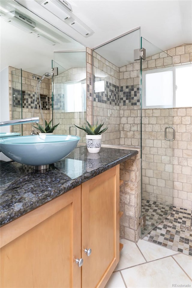 bathroom with tile walls, tasteful backsplash, a stall shower, vanity, and tile patterned flooring