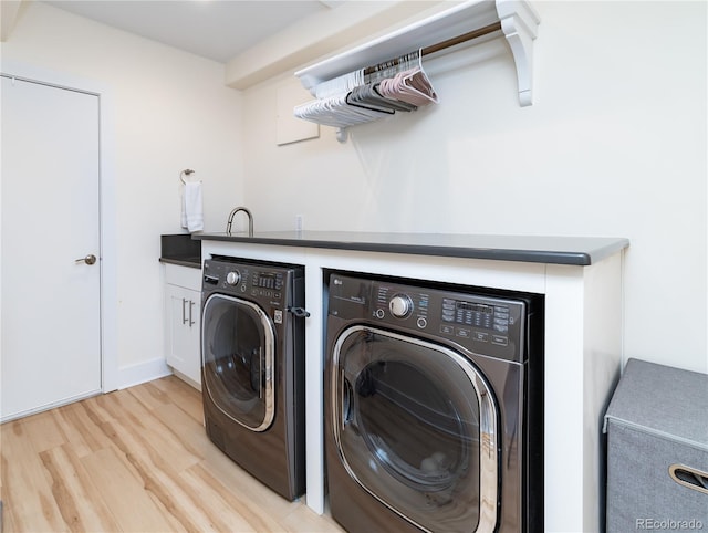 laundry area with light wood-type flooring, cabinet space, and independent washer and dryer