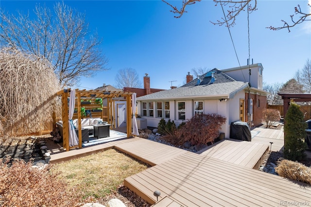 back of house with roof with shingles, stucco siding, fence, a pergola, and a wooden deck