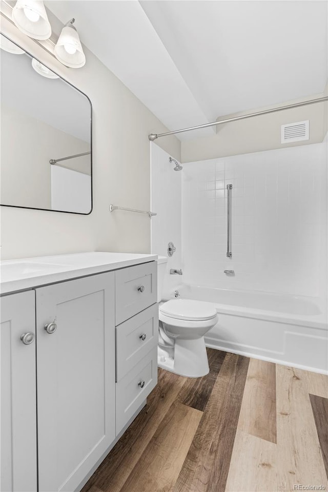 full bath featuring visible vents, wood finished floors, vanity, toilet, and bathing tub / shower combination