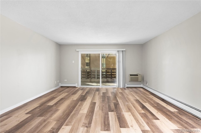 spare room with baseboards, a wall mounted AC, wood finished floors, and baseboard heating