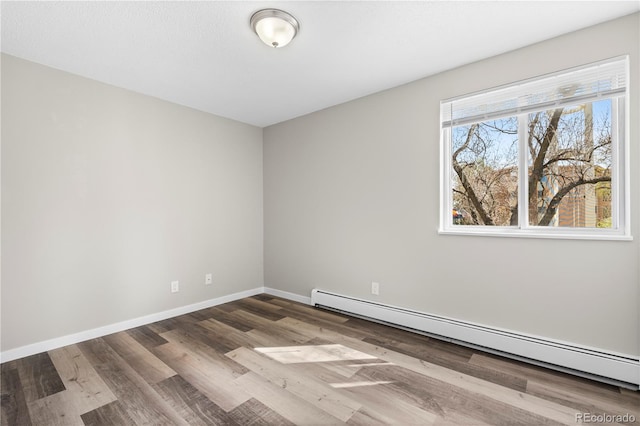 unfurnished room with baseboards, wood finished floors, and a baseboard radiator