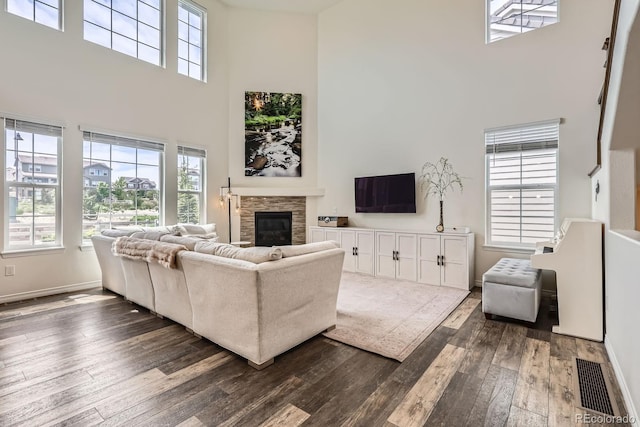 3162 Grizzly Peak Dr, Broomfield, CO 80023 - living area with a towering ceiling, dark wood finished floors, a stone fireplace, baseboards, and healthy amount of natural light