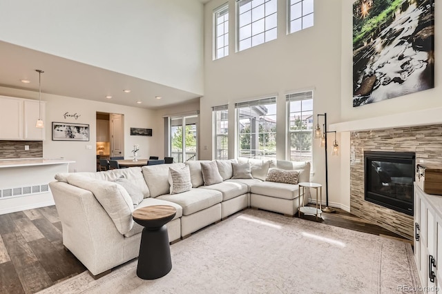 3162 Grizzly Peak Dr, Broomfield, CO 80023 - living room featuring wood finished floors, a high ceiling, a tiled fireplace, and recessed lighting