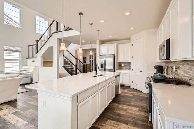 3162 Grizzly Peak Dr, Broomfield, CO 80023 - kitchen with appliances with stainless steel finishes, decorative backsplash, dark wood-style floors, white cabinetry, and a high ceiling