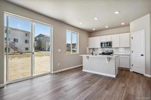 kitchen with white cabinetry, sink, stainless steel appliances, tasteful backsplash, and light hardwood / wood-style flooring