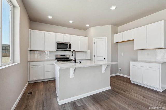 kitchen featuring a kitchen island with sink, sink, dark hardwood / wood-style flooring, white cabinetry, and stainless steel appliances