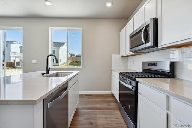 kitchen with decorative backsplash, appliances with stainless steel finishes, sink, light hardwood / wood-style floors, and white cabinetry